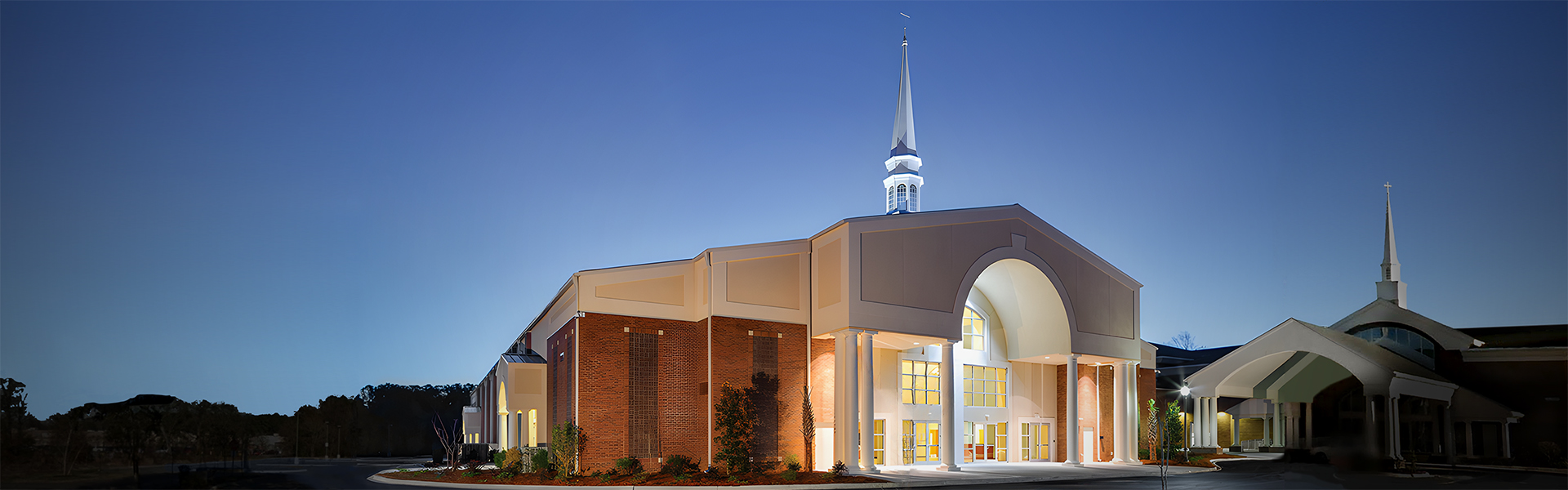 Mount Moriah Missionary Baptist Church at dusk with an arched glass entry and steeple above a covered entrance
